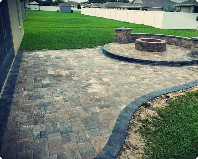 Paver patio with a raised fire pit and a dark soldier-course border